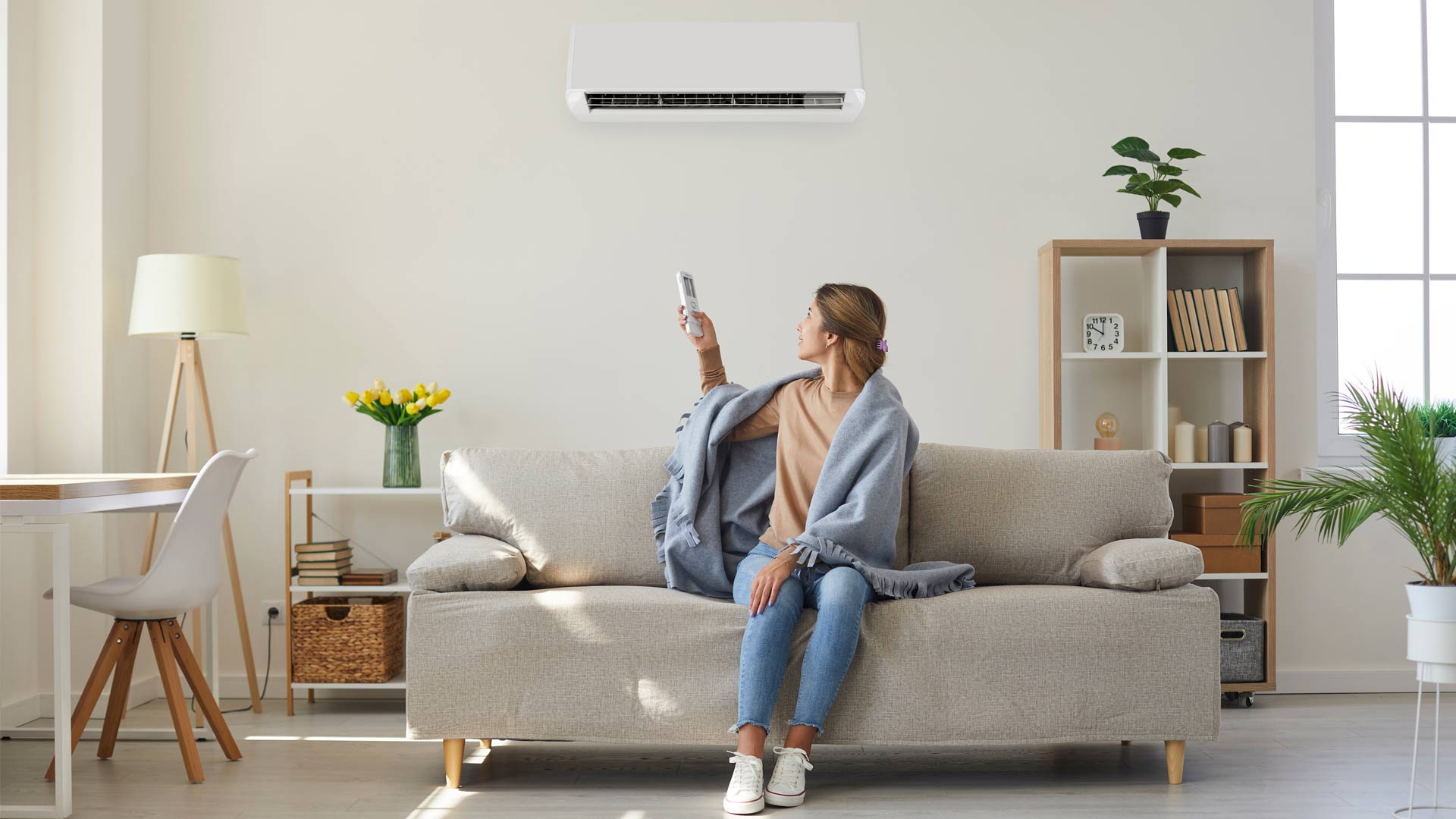 Woman on couch using air conditioning remote